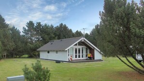 Een klein, laag huis met schuine dak en een veranda.