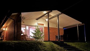 A building with a brick exterior, a covered outdoor area with steps leading up to a door, and a small Christmas tree.