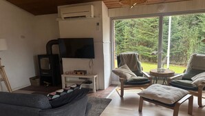 A living room with a sofa, two armchairs, a coffee table, a TV, and a fireplace.