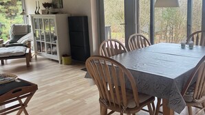 A dining area with a table and chairs, a cabinet, and a window with a view of trees.