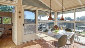 A spacious dining area with a table and chairs, large windows, and a view of the outdoors. - "Arntraud" - 250m from the sea by Interhome (Knebel)