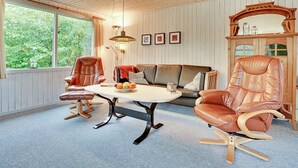 A cozy room with a wooden ceiling, a large window with curtains, a leather sofa, two leather chairs, a small table with fruit, and a cabinet with decorative items. - "Leny" - 450m to the fjord by Interhome (Tarm)
