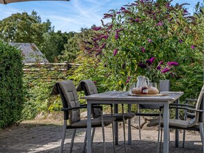 An outdoor table with chairs, a pitcher, and a loaf of bread.