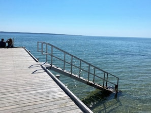 A wooden pier extending into calm water with a metal railing.