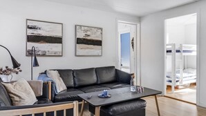 En moderne stue med en sort lædersofa, et træbord og to abstrakte malerier på væggen.