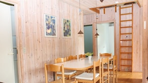 Un coin repas avec une table et des chaises en bois, une plante posée sur la table et une échelle en bois appuyée contre le mur.