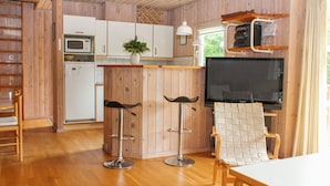Une cuisine compacte avec des meubles en bois, un four à micro-ondes, un évier et un coin bar avec des tabourets.