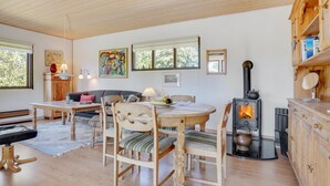 Ein gemütliches Wohnzimmer mit einem Holzesstisch, Stühlen, einer Couch und einem Kaminofen.