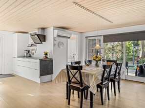 Eine moderne Küche mit weißen Schränken, einem eingebauten Backofen und einem großen Fenster mit Blick auf einen Garten.