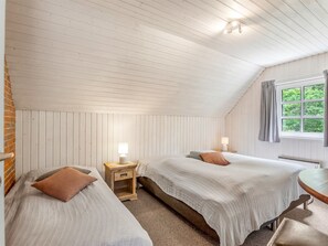 A bedroom with two beds, a window with curtains, and a wooden nightstand with a lamp. - "Pauna" - 50m from the sea by Interhome (Væggerløse)