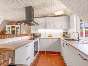 Eine moderne Küche mit weißen Schränken, einer Steinrückwand, einem eingebauten Backofen und einem großen Fenster.