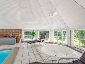 Ein Wintergarten mit Pool, einer Liege, einem Whirlpool und einer Backsteinmauer.