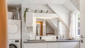 Een moderne keuken met een ingebouwde wasmachine, een grote spiegel en een raam met uitzicht.