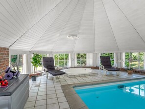 A sunlit indoor swimming pool area with a brick wall, tiled floor, and lounge chairs. - "Pauna" - 50m from the sea by Interhome (Væggerløse)