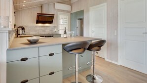 A modern kitchen with a central island, bar stools, and a built-in oven. - "Justiina" - 800m from the sea by Interhome (Væggerløse)
