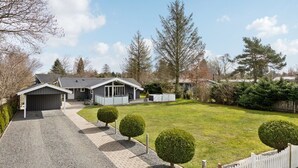 A modern house with a garage, a covered patio, and a well-maintained lawn with trimmed bushes. - "Justiina" - 800m from the sea by Interhome (Væggerløse)
