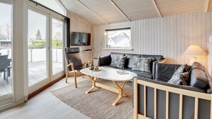 A modern living room with a sofa, coffee table, and chairs, a TV mounted on the wall, and a large sliding glass door leading to an outdoor area. - "Justiina" - 800m from the sea by Interhome (Væggerløse)