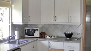 A kitchen with white cabinets, a microwave, a sink, and a wooden countertop. - "Nitis" - 200m from the sea by Interhome (Væggerløse)