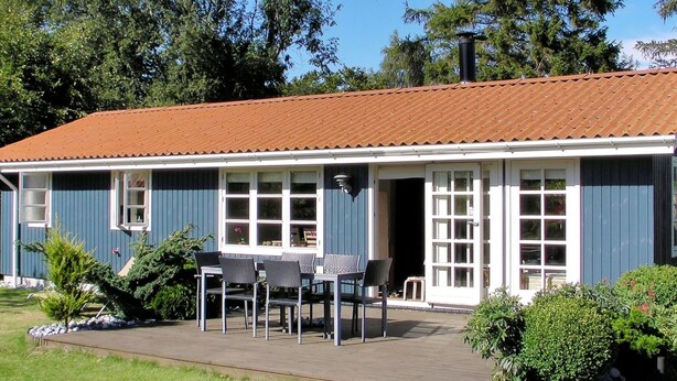 A two-story house with a blue exterior and a brown roof. There is a patio with a table and chairs in front of the house. - "Nitis" - 200m from the sea by Interhome (Væggerløse)