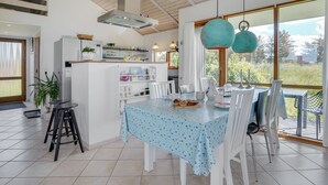 Une cuisine moderne avec des meubles blancs, un îlot central et un coin repas comprenant une table et des chaises.