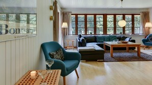 A spacious living room with a large window, a blue armchair, a black sofa, and a wooden coffee table. - "Satzur" - 800m from the sea by Interhome (Blåvand)