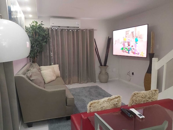 A living room with a sofa, a coffee table, a TV, and a staircase.