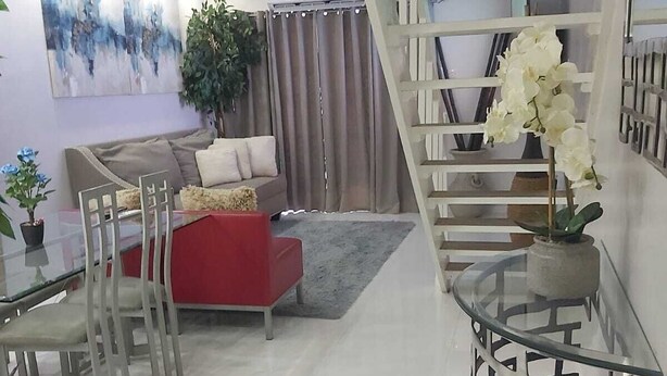 Uma sala de estar moderna com um sofá vermelho, mesa de centro de vidro e escada com guarda-corrimão de vidro.