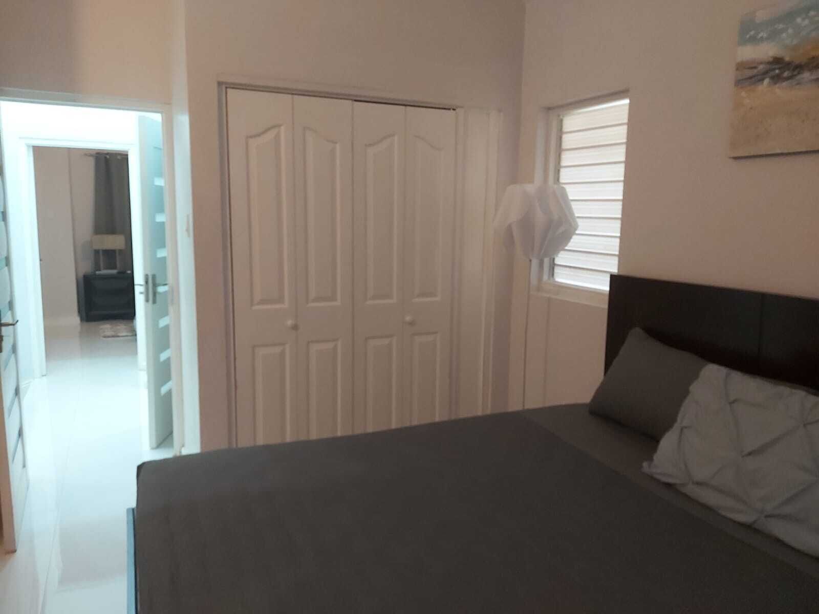 A bedroom with a bed, a wardrobe, a window, and a door.