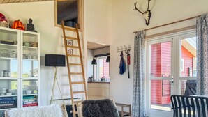 Ein gemütliches Wohnzimmer mit einer Leiter, einem Bücherregal und Blick auf ein rotes Gebäude durch eine Glastür.