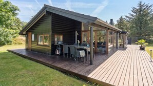 Een moderne cabin met een terras, buitenzitplaatsen en een overdekte patio.