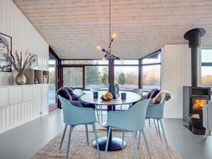 Et moderne spiseområde med et rundt bord, fire stole, et sofabord og en pejs.