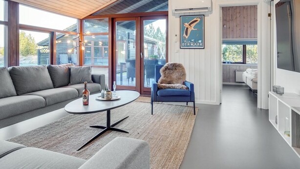 Een moderne woonkamer met een grijze bank, een ronde salontafel en een blauwe fauteuil.