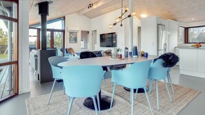 Een moderne keuken met een eetgedeelte, met een grote tafel, lichtblauwe stoelen en een hanglamp.