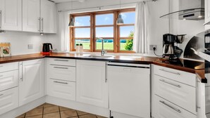 A modern kitchen with white cabinets, a wooden countertop, a built-in dishwasher, and a coffee machine. - "Aliza" - 300m to the fjord by Interhome (Roslev)