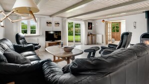 A spacious living room with a large leather sofa, a television, and a fireplace. - "Aliza" - 300m to the fjord by Interhome (Roslev)