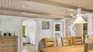 A dining area with a wooden table and chairs, a white cabinet, and a hanging light fixture. - "Aliza" - 300m to the fjord by Interhome (Roslev)