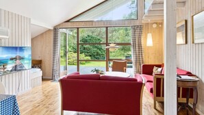 A spacious room with a large window offering a view of greenery and a distant landscape. There is a red sofa, a small table, and a chair. - "Wilgrib" - 400m from the sea by Interhome (Højby)
