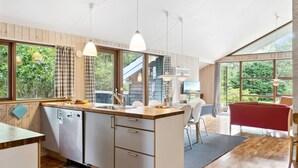 A modern kitchen with a wooden countertop, a sink, and a dining area with a red sofa and a TV. - "Wilgrib" - 400m from the sea by Interhome (Højby)
