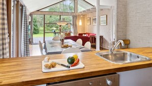 A modern kitchen with wooden countertops, a sink, and a dining area with a red sofa and table. - "Wilgrib" - 400m from the sea by Interhome (Højby)
