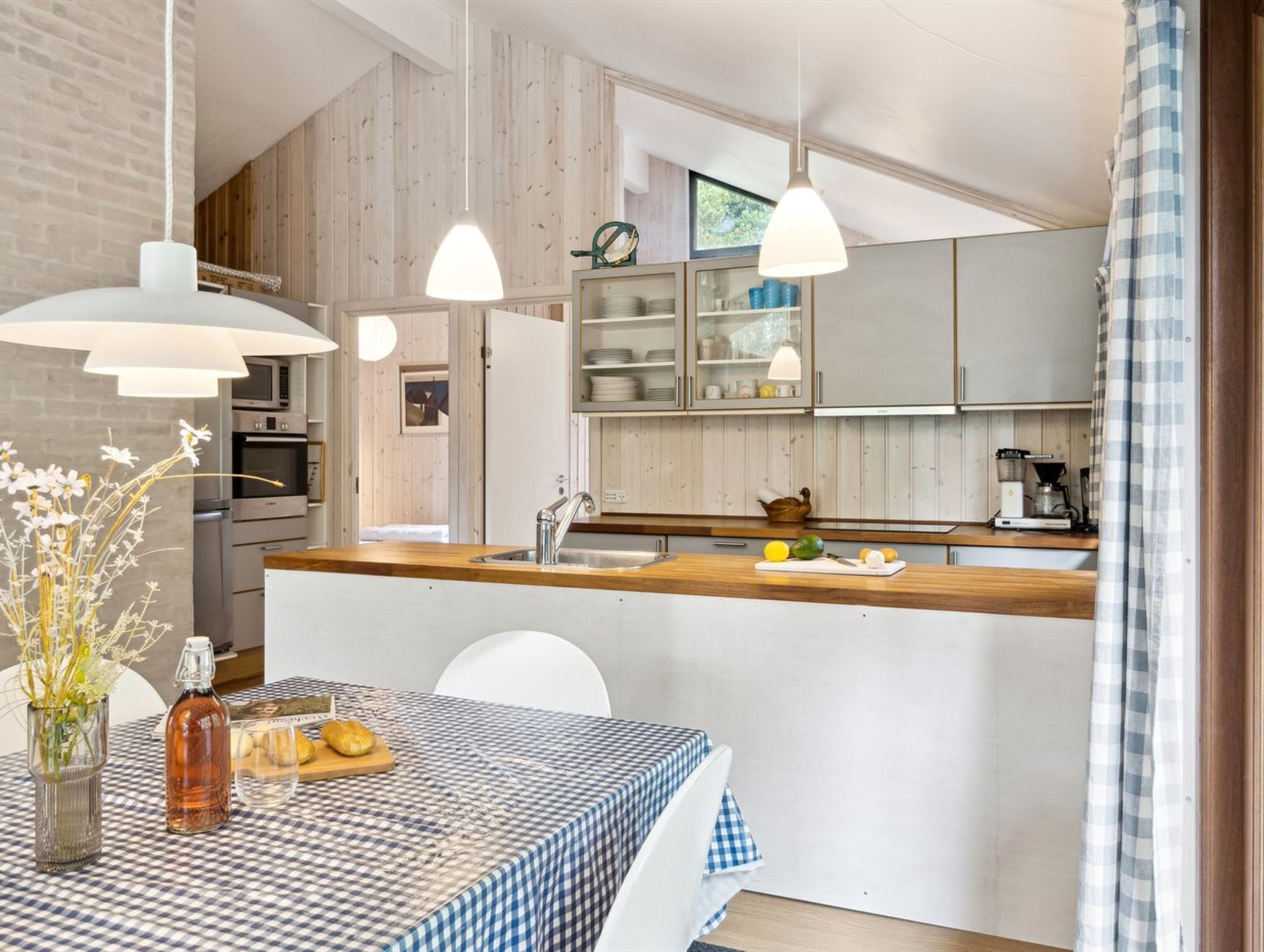 Une cuisine moderne avec des meubles en bois, un îlot central et des luminaires suspendus.