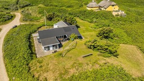 Een kustwoning met een huis, terras en uitzicht op zee.