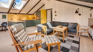 Un espacio habitable estilo loft con cocina, vigas de madera, un sofá y una mesa de comedor.