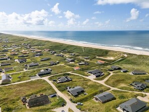 An aerial view of a coastal residential area with houses, roads, and a beach.