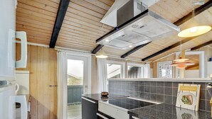Une cuisine moderne avec un plan de travail noir, des armoires blanches et un plafond en bois.