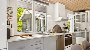Una cocina moderna con armarios grises, un lavamanos de acero inoxidable y un horno empotrado.