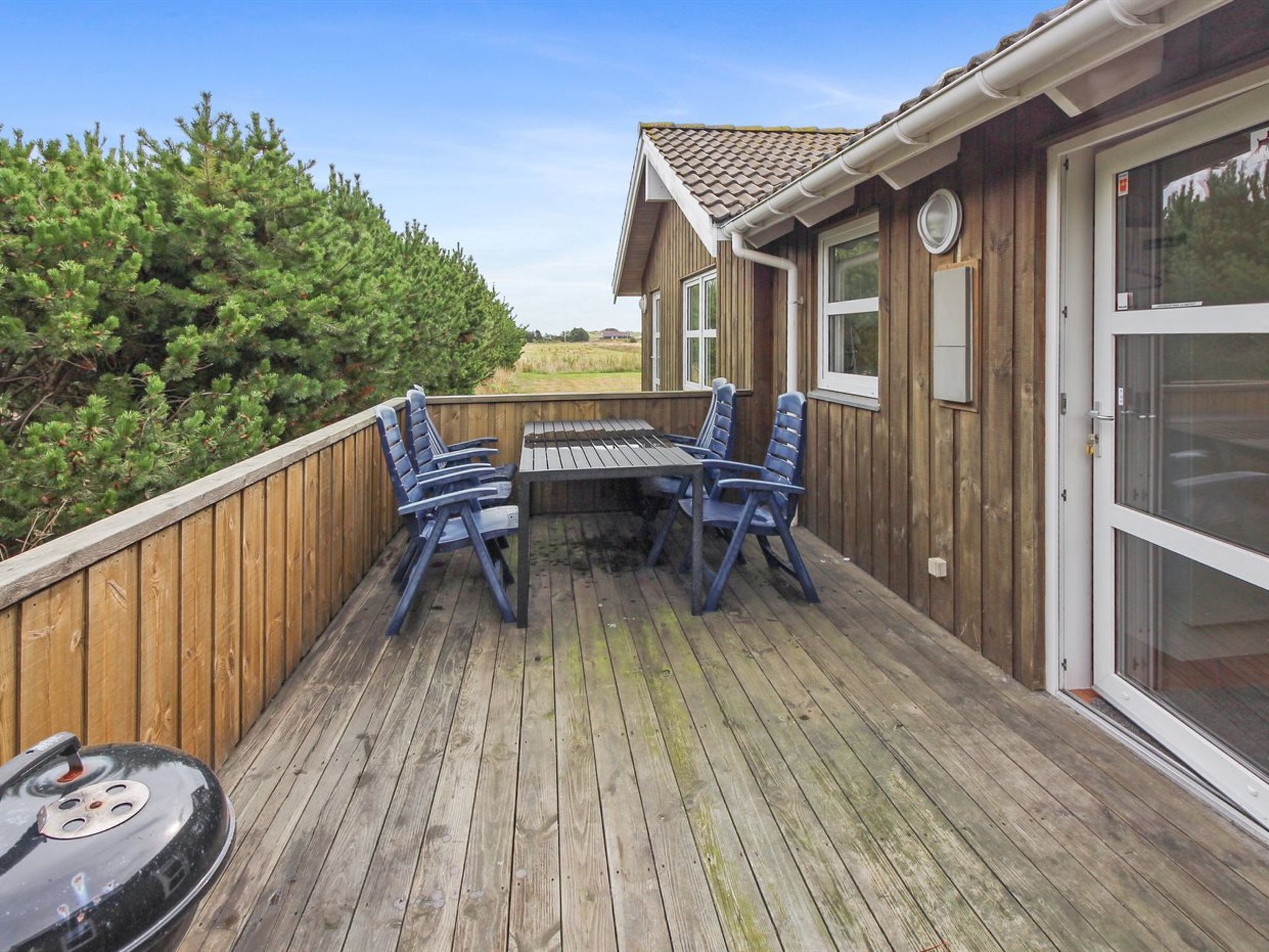 A wooden deck with a grill, a table, and four chairs.