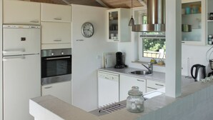 A modern kitchen with white cabinetry, a stainless steel range hood, a clock on the wall, and a window providing natural light. - "Calina" - 300m from the sea by Interhome (Sæby)