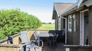 A wooden deck with a table and chairs, a wooden fence, and a house with a tiled roof. - "Calina" - 300m from the sea by Interhome (Sæby)