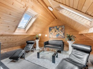A cozy attic room with a sloped ceiling, a large painting, and a seating area with a sofa and two chairs. - "Yvonna" - 350m to the fjord by Interhome (Skjern)