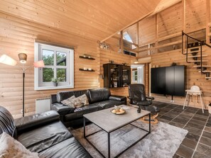 A modern log cabin interior with a black leather sofa, a coffee table, a TV, and a staircase. - "Yvonna" - 350m to the fjord by Interhome (Skjern)